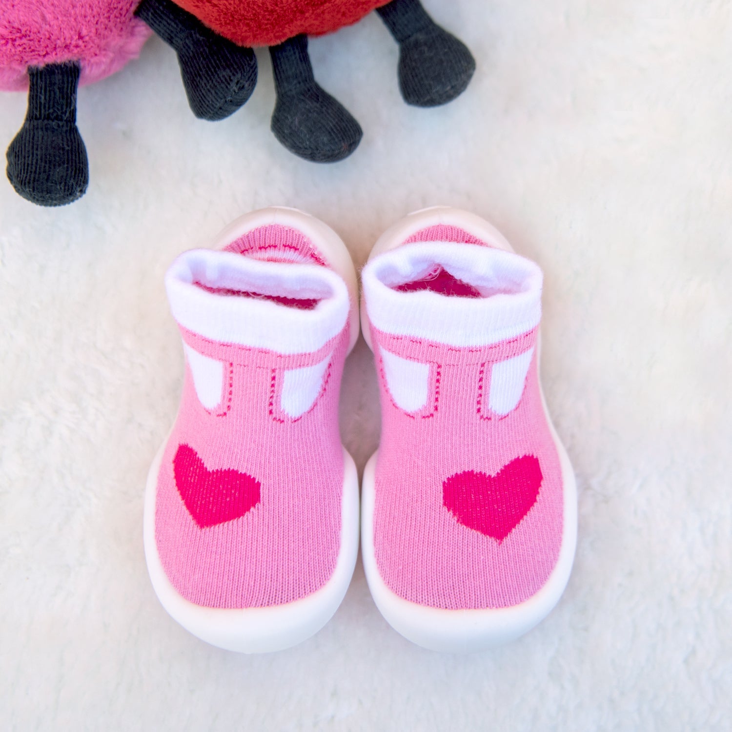 Pink baby sock-shoes with white trim and hearts.