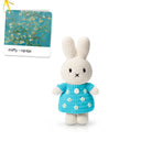 Crocheted bunny toy in a blue dress with a card in the background