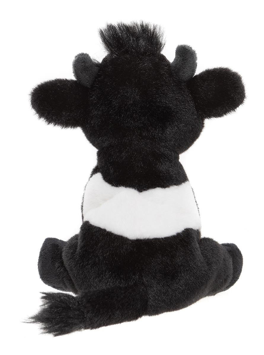Black and white plush cow toy on a white background