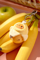 Plush keychain shaped like a banana with a face attached to a bunch of bananas.