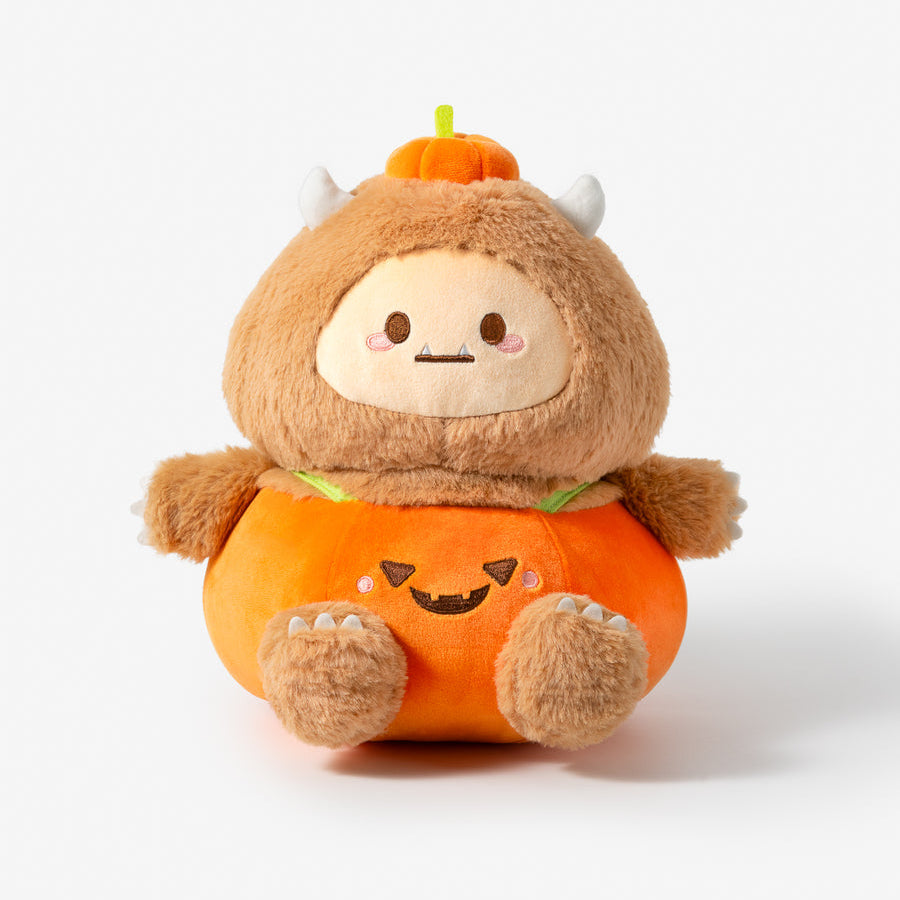 A cute plush toy character dressed in a pumpkin costume, featuring a brown fuzzy monster body with small horns, a smiling face, and an orange pumpkin-shaped outfit with a jack-o'-lantern face.