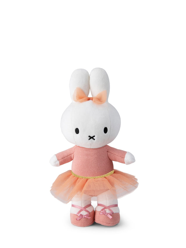 Plush toy rabbit in a pink dress with a bow on a white background