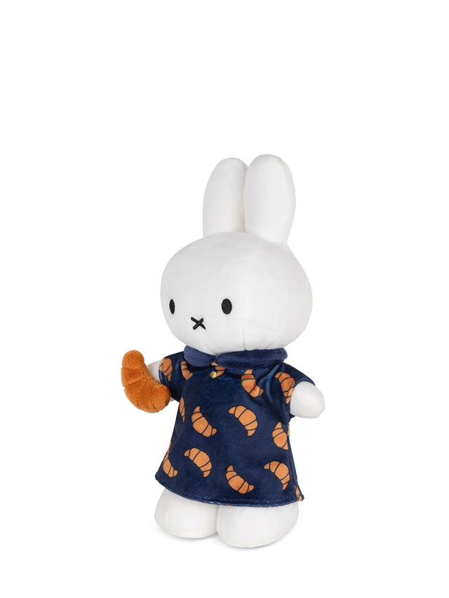 White plush toy rabbit wearing a navy dress with orange patterns on a white background