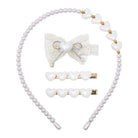 A hair accessory set featuring a pearl-bead headband with white heart-shaped beads and gold accents, a white lace bow hair clip with a pearl center, and two white heart-barrette hair clips with gold metal bases, all arranged on a plain white background.