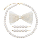 A pearl-themed hair accessory set featuring a long pearl necklace with a gold chain extender, a cream lace bow with a central pearl, two pearl-barrel hair clips with gold metal ends, and two matching pearl hair pins, all arranged on a solid white background.