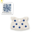 Crocheted off-white purse with blue flower detailing.