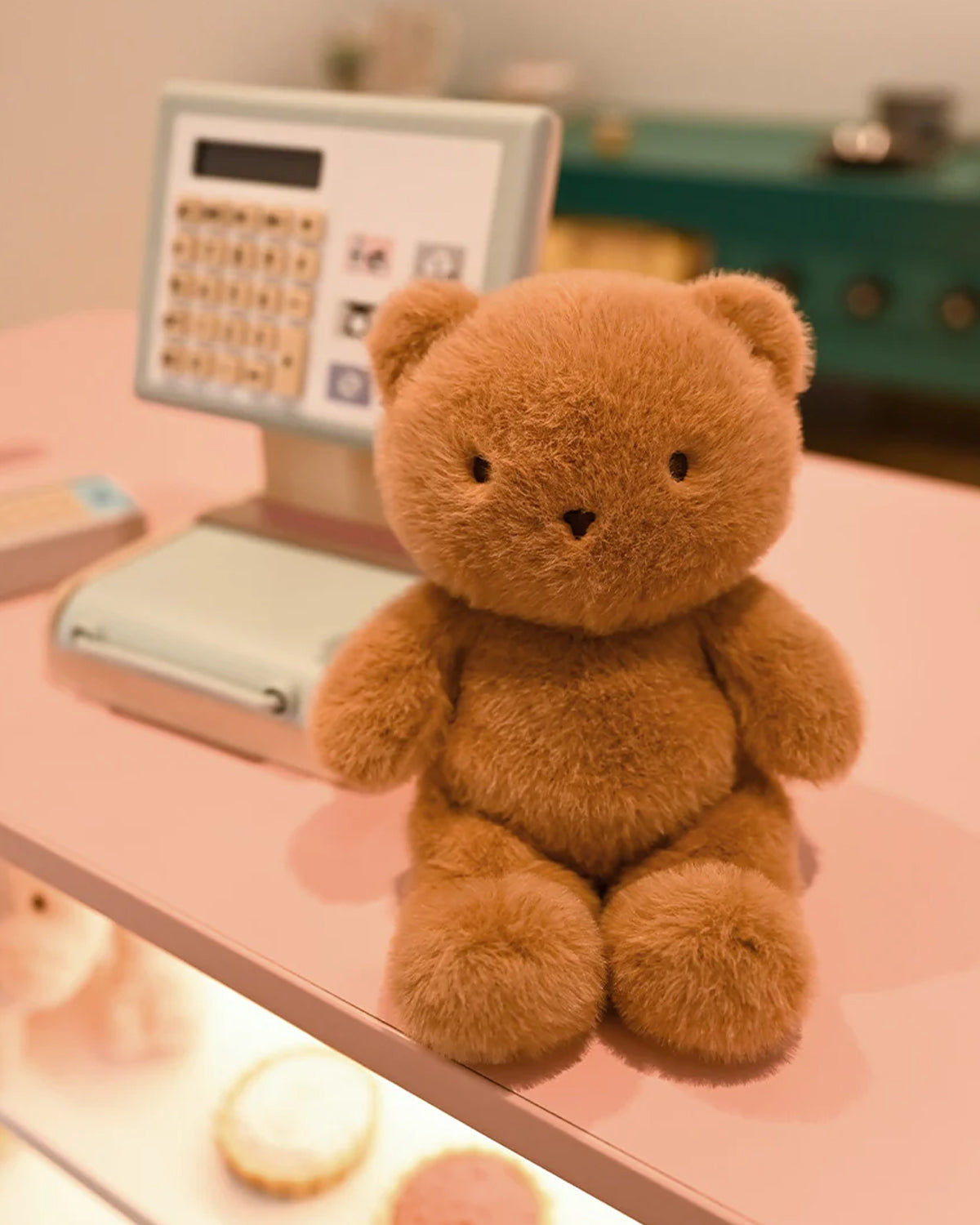 Brown teddy bear on a pink surface with a blurred background