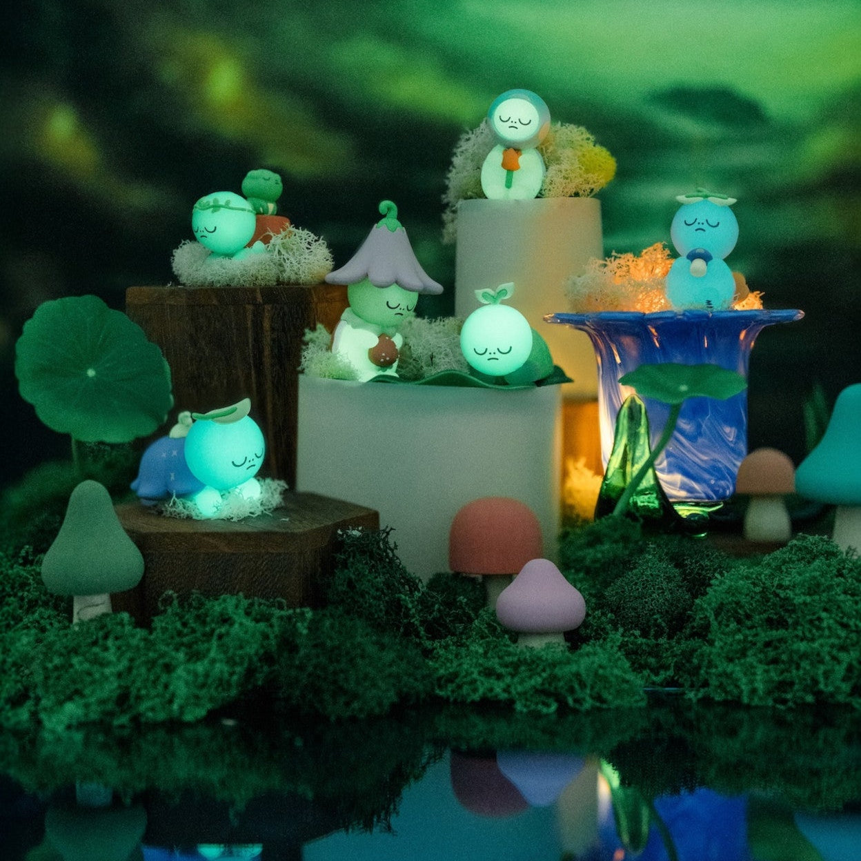 Fairy garden scene with various small figurines and plants against a dark forest background.