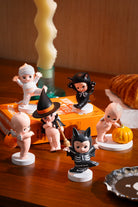 Halloween-themed figurines on a wooden surface with a candle and decorative items.