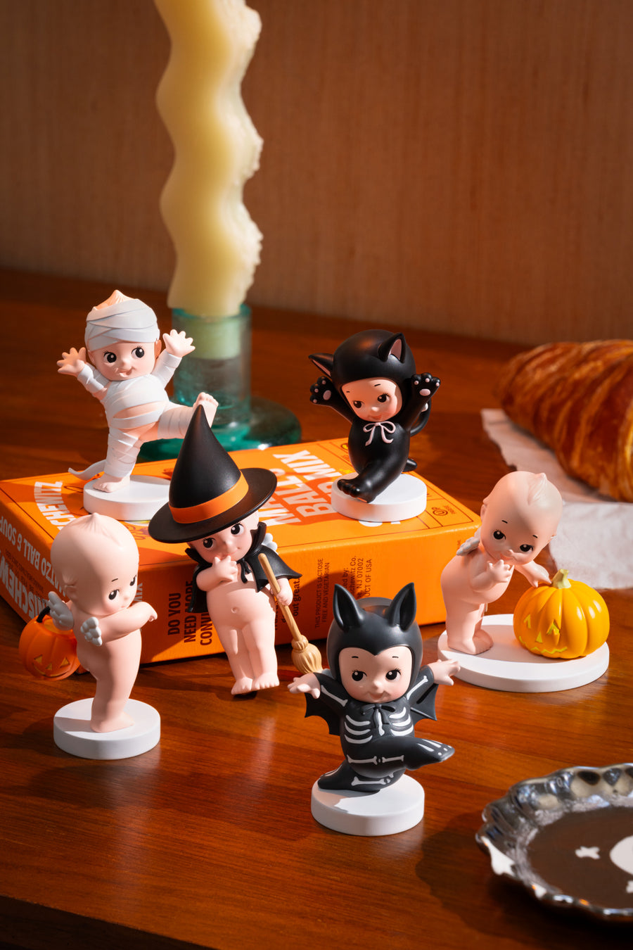 Halloween-themed figurines on a wooden surface with a candle and decorative items.