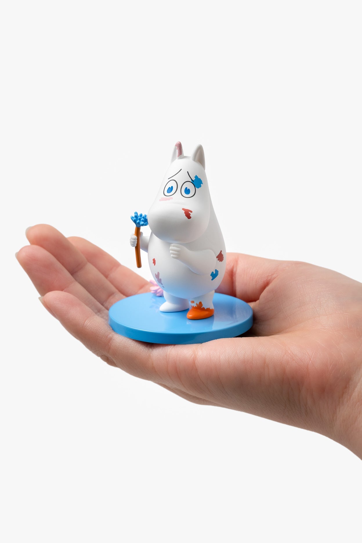 Hand holding a small figurine of a cartoon character on a white background
