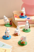 Set of small figurines on a wooden surface with a book in the background
