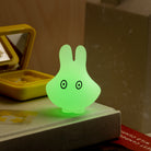 Green glowing rabbit-shaped night light on a surface with a blurred background