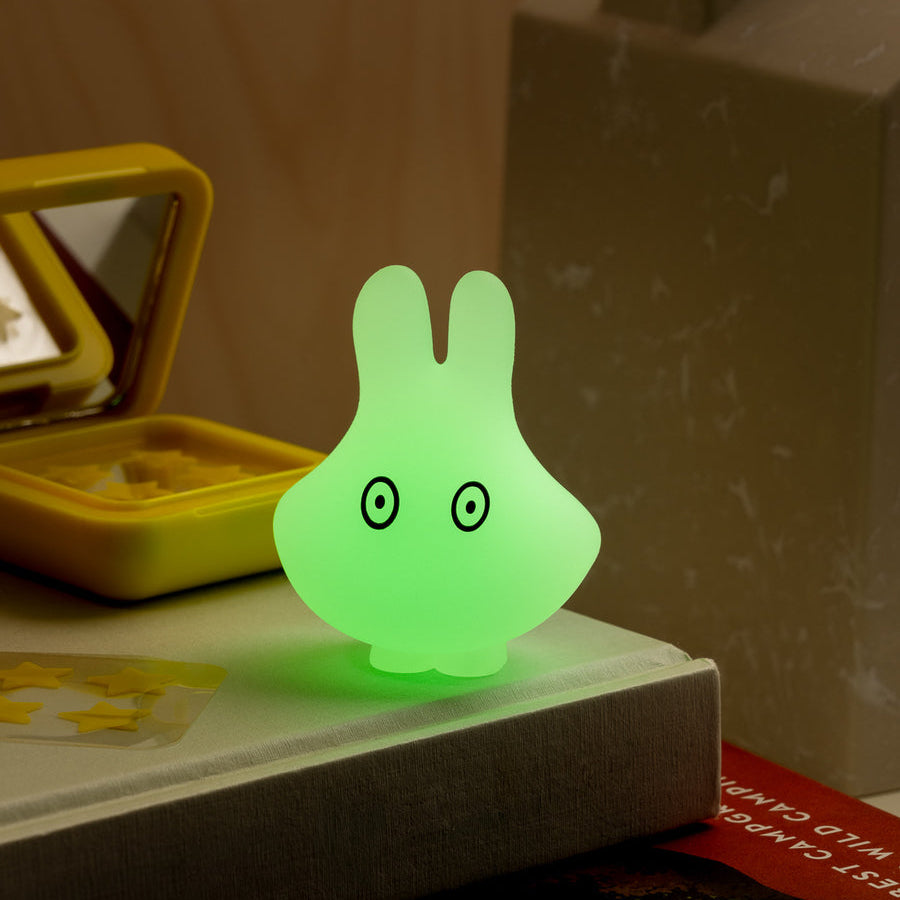 Green glowing rabbit-shaped night light on a surface with a blurred background