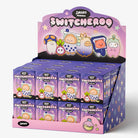 A retail display box filled with small purple Swomo Switcheroo mystery blind boxes, shown on a clean light gray studio background.