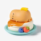 A cute, stylized clay figurine of a sleeping character resembling Cuddly, styled as a breakfast sandwich with butter, syrup, a biscuit, and small fruit candies on a light blue plate, set against a plain white background.
