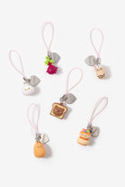 Six cute, small food-themed charm keychains with pink loops and silver heart-shaped tags, arranged on a clean white background. The charms include a white bunny, a green frog and pink strawberry, a bubble tea cup, a slice of toast with a bear face, a yellow character, and a hamburger.