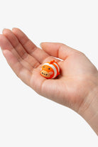 Small clownfish figurine held in a hand against a white background