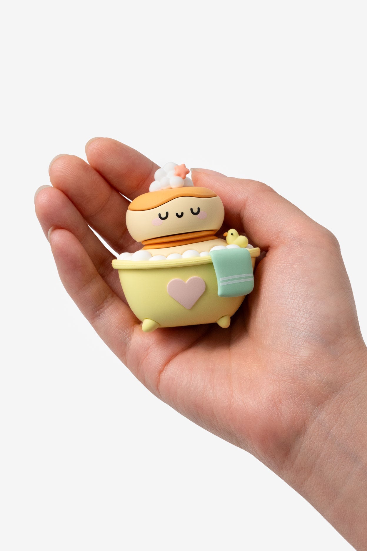 Hand holding a small, cute toy figure of a character in a bathtub with a towel.
