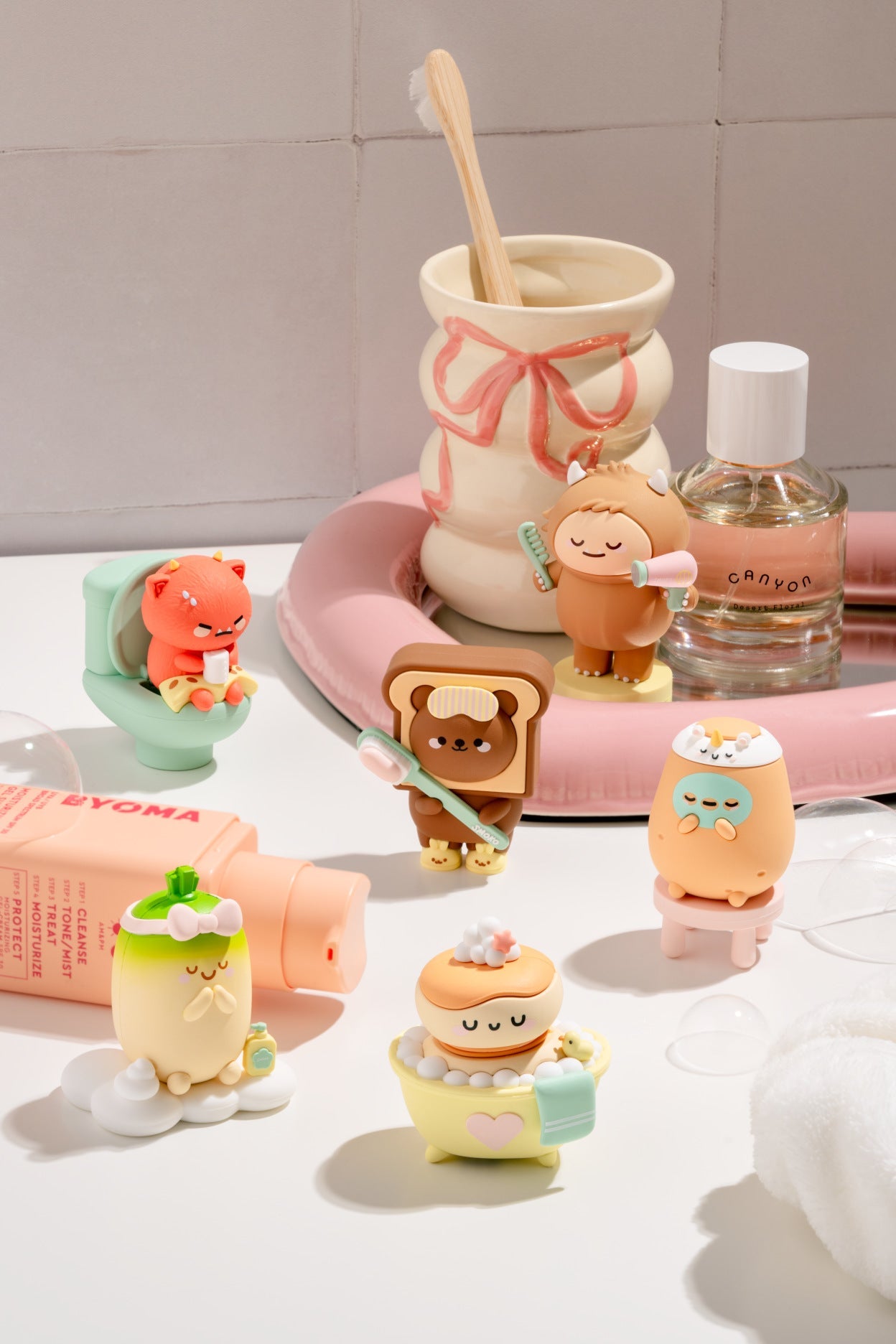 Set of small figurines resembling cartoon characters on a bathroom counter with hygiene products.