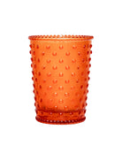 Orange glass tumbler with a textured surface on a white background