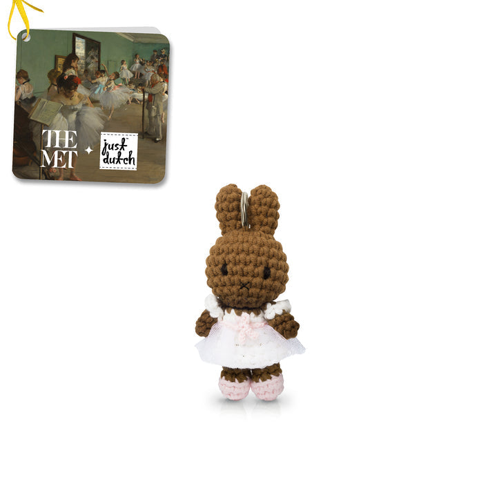 Crocheted rabbit plush toy with a dress, branded with The Met and Just Dutch, on a white background.