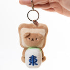 Plush keychain shaped like a bear in a toast costume held by a hand against a white background