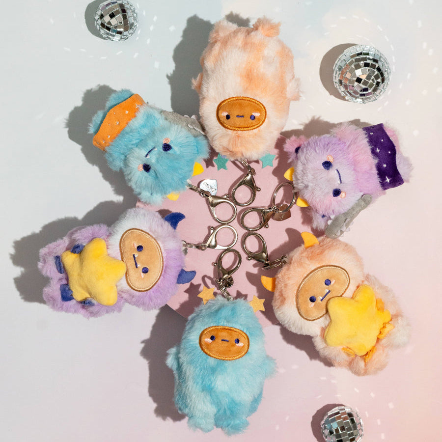 Set of colorful plush keychains with cartoon faces on a light background