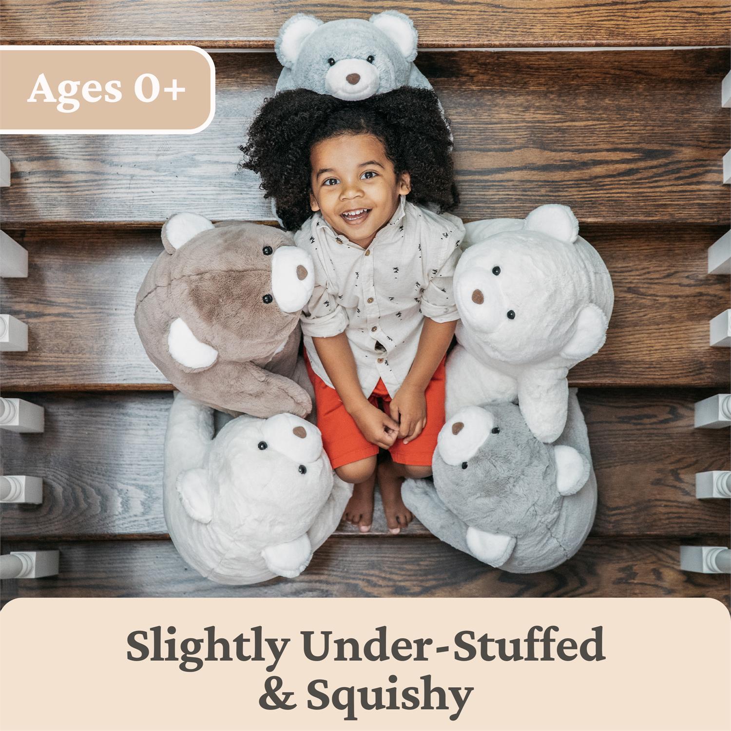 Child sitting among plush toys on a wooden floor with text indicating age suitability and product description.