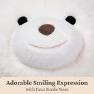 Close-up of a plush toy with a smiling expression and faux suede nose on a white background.