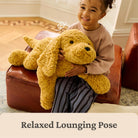 Child holding a large yellow teddy bear on a brown leather ottoman.