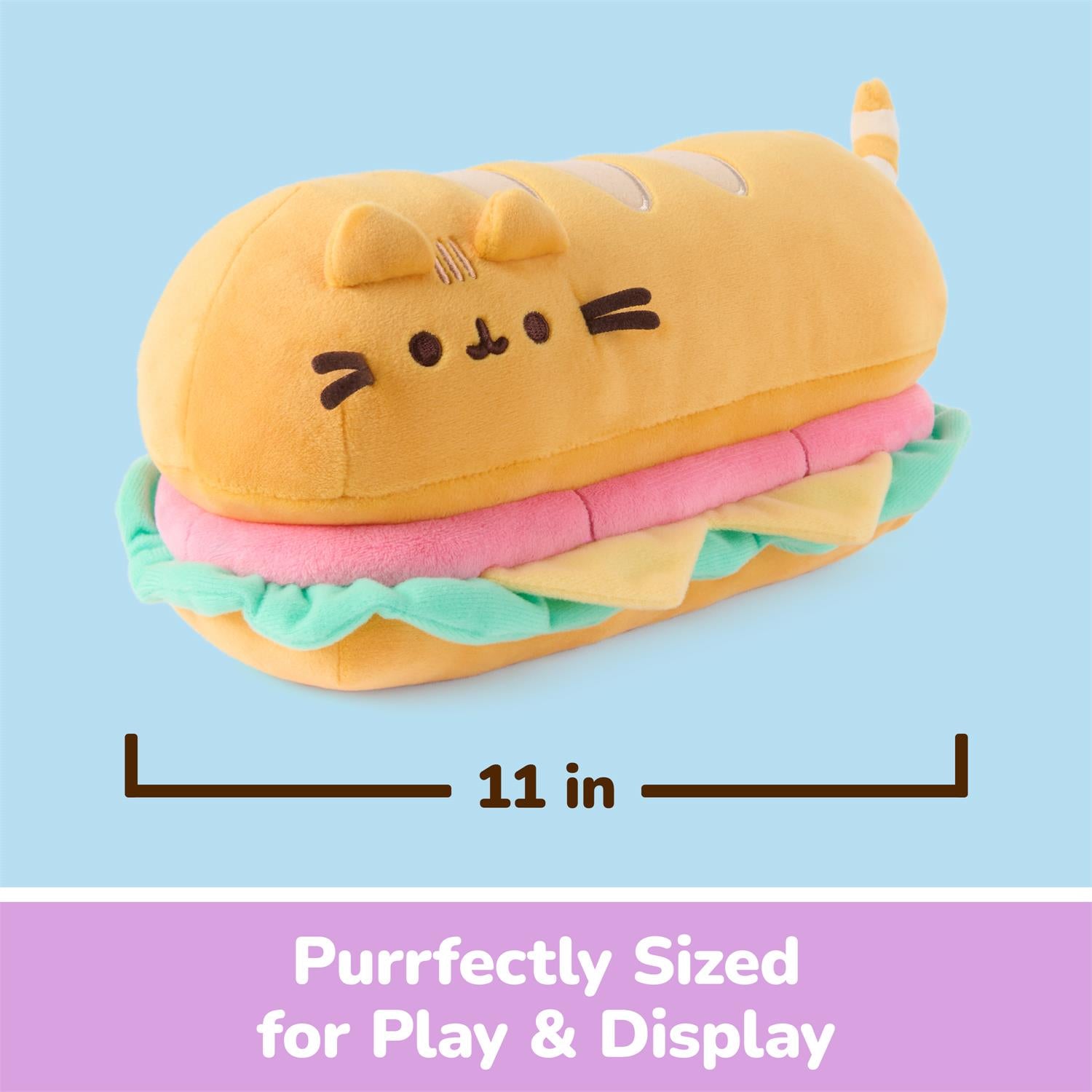 A plush sandwich-shaped pillow in yellow, pink, and mint green with a cat face, shown on a light blue background with a measurement label of 11 in and a purple banner reading 'Purrfectly Sized for Play & Display'.