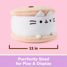 A plush cat-shaped storage box or container shown on a pink background with a dimension line indicating 11 inches wide. The product is white with beige top and bottom layers and simple embroidered facial features.