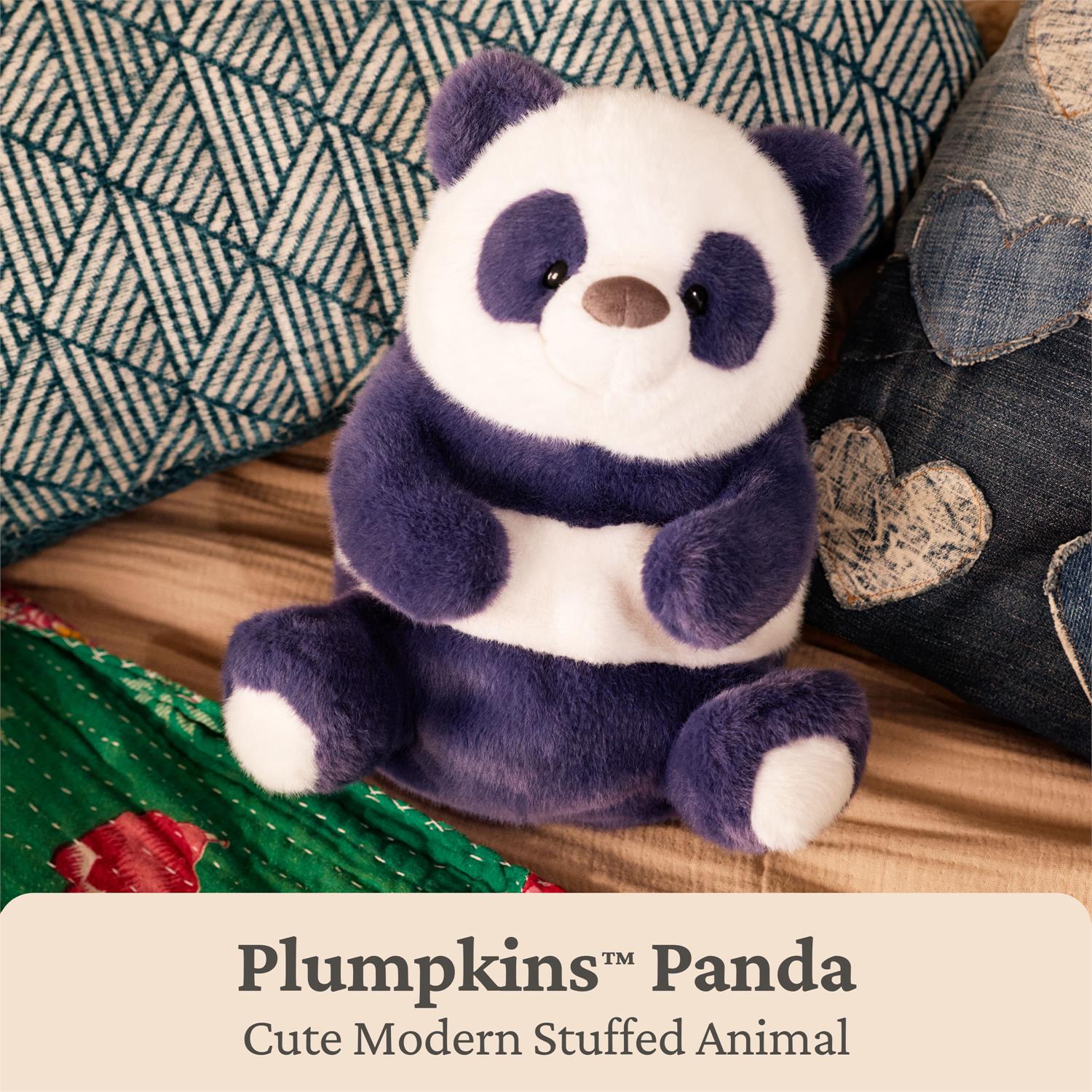 A plush panda toy sitting on a wooden surface with decorative pillows around it. The text overlay at the bottom reads 'Pumpkins™ Panda Cute Modern Stuffed Animal'.