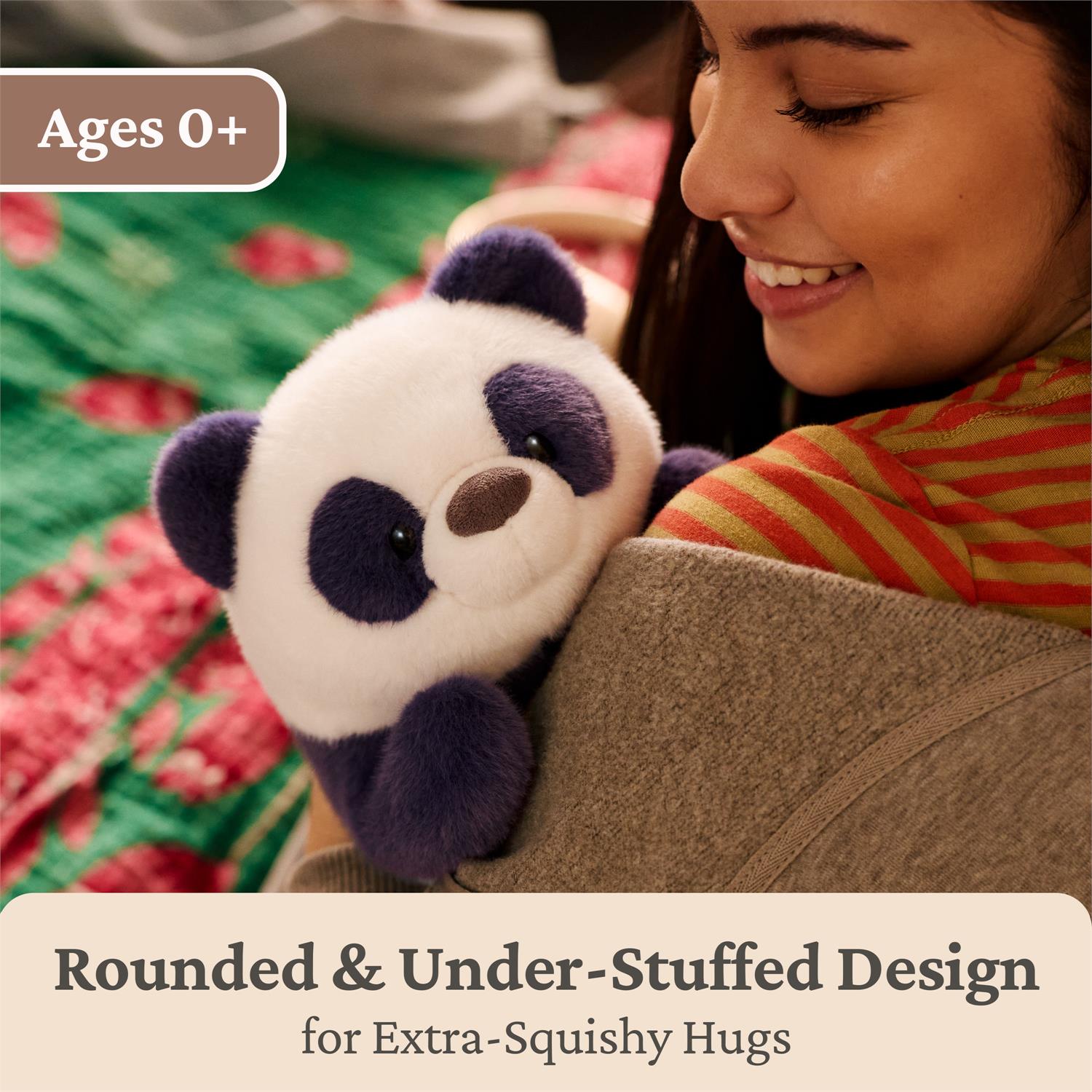A smiling woman in a striped shirt hugs a plush panda toy. The image includes text overlays reading 'Ages 0+' and 'Rounded & Under-Stuffed Design for Extra-Squishy Hugs'.