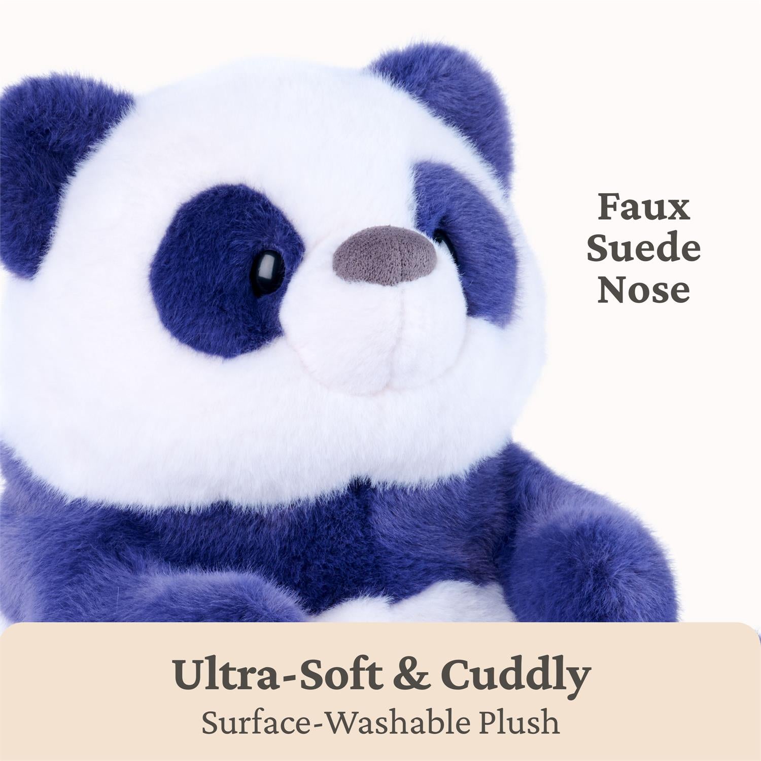 A close-up of a plush panda toy with white and dark blue fur, black eyes, and a brown nose, on a light background with text reading 'Faux Suede Nose' and 'Ultra-Soft & Cuddly Surface-Washable Plush'.