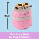 A Pusheen plush toy styled like a round container, wearing pink polka-dot pants and yellow sunglasses, shown on a light blue background with a measurement marker indicating 9.5 in height and a purple banner reading 'Purrfectly Sized for Play & Display'.