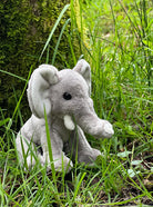 Plush elephant toy in a grassy outdoor setting