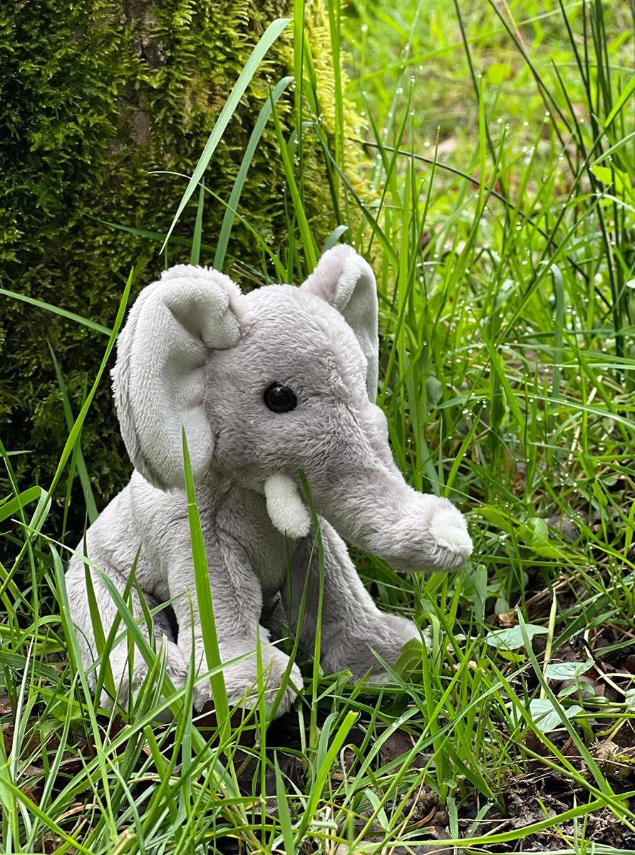 Plush elephant toy in a grassy outdoor setting