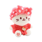 White plush cat toy in a pink polka-dot headband and matching shirt with cat-shaped button.