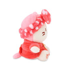 Side view of a pink plush toy with a spotted hat and red outfit.