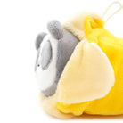 Close-up of a gray and white plush toy sleeping inside a yellow hooded blanket.