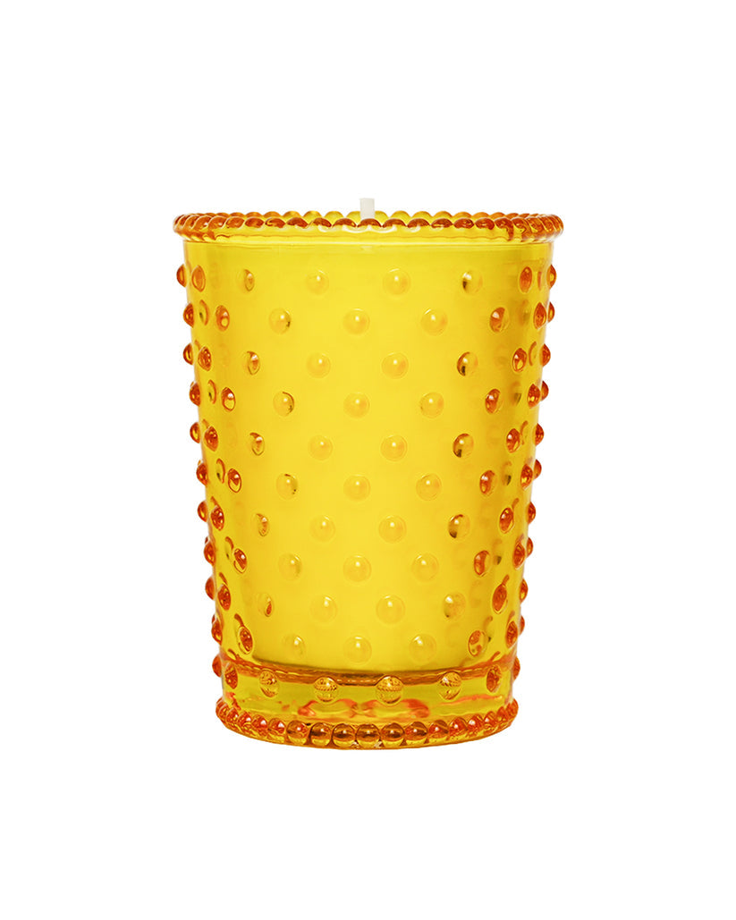 Yellow glass tumbler with a textured rim on a white background