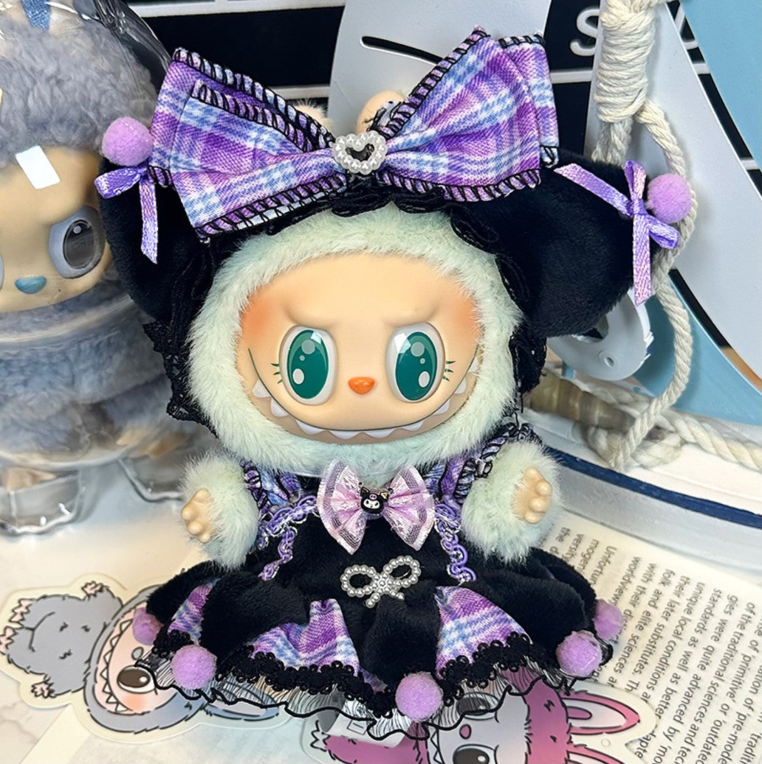 A doll wearing a black and purple dress with a large plaid bow.