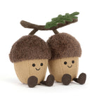 Two plush acorns with faces and a branch on a white background
