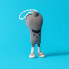 A small plush toy shaped like a gray coffee cup with a smiling face, white socks, and gray shoes, attached to a white and blue striped rope loop, standing on a bright blue background.