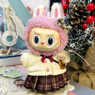 A doll in a pink fuzzy bunny hat with a plaid skirt and knitted sweater.