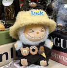 Close-up of a toy figure with a shaggy hat, wearing overalls with food-shaped decorations.