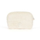 An off-white faux fur cosmetic pouch with a small silver zipper pull and a circular embossed logo on the front, set against a plain white background.