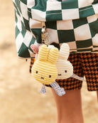 Two plush bunny keychains hanging from a keychain holder with a blurred background.